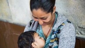 A woman looking down at her sleeping child.